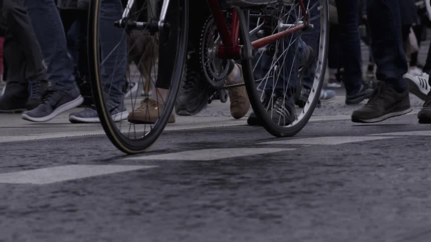 People traveling down the road by foot and bike