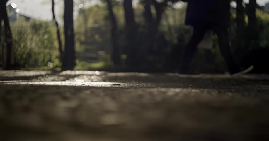 People walk along the sidewalk in the shaded area