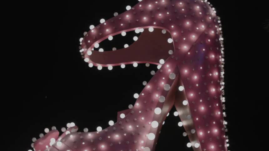 A neon light shape like a shoe illuminates the night