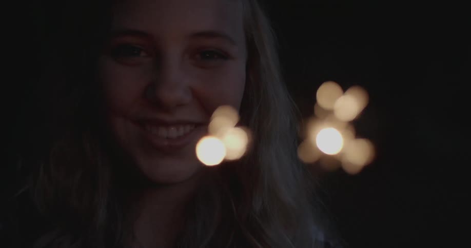 A woman holds sparklers as they burn and spark
