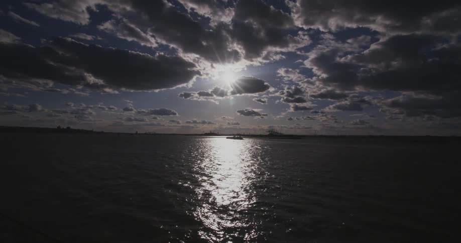 The sunshine glistens off the water with clouds above