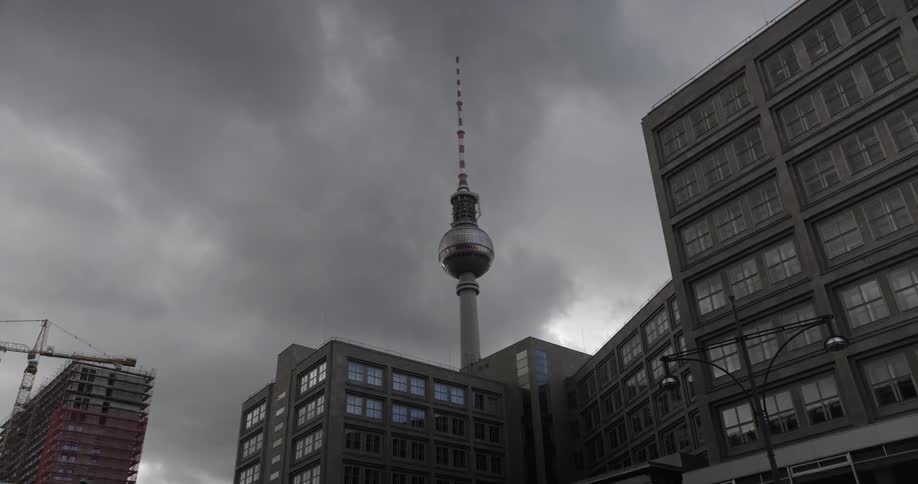 A radio antenna and city buildings on a cloudy day