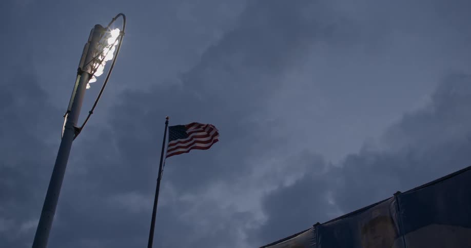 An american flag breezes in the wind near stadium lights
