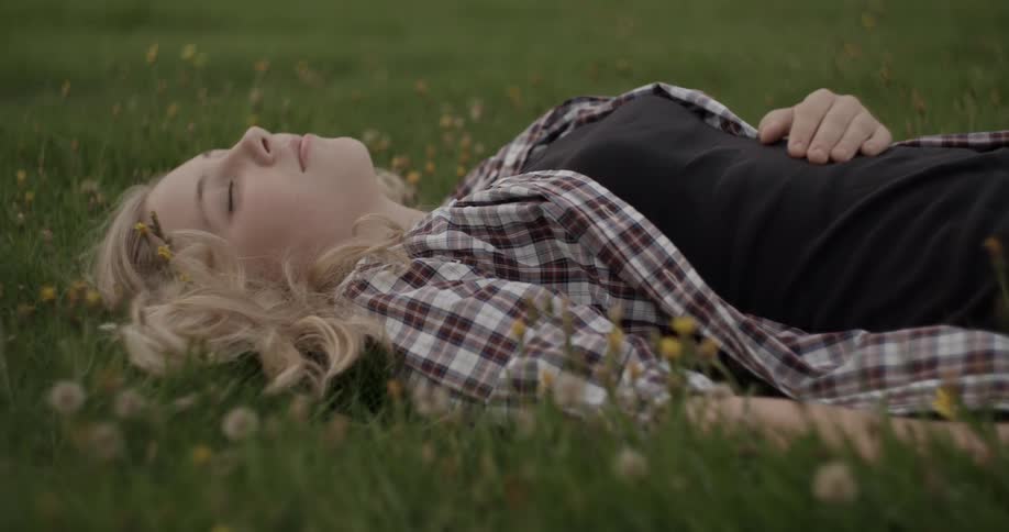 A young woman lies in the green grass relaxing