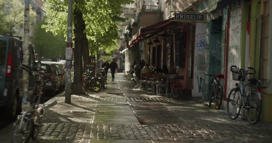 A city sidewalk with people walking and sitting at a cafe