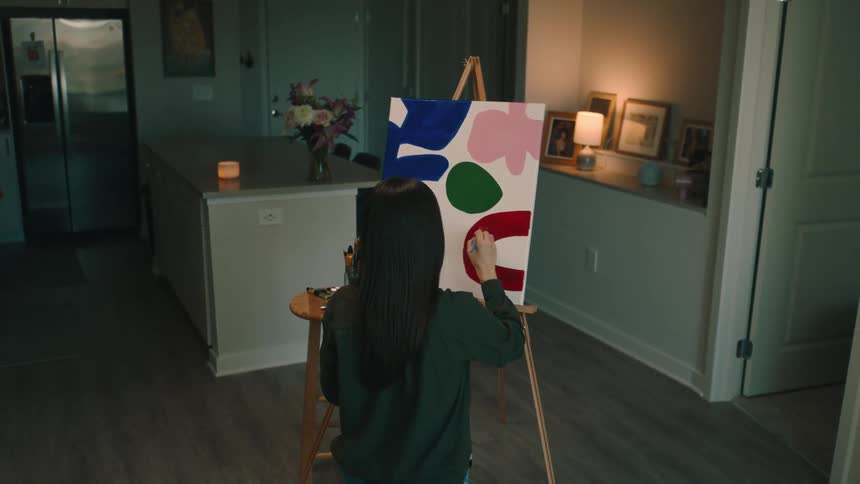 Woman crouched and facing away painting a canvas
