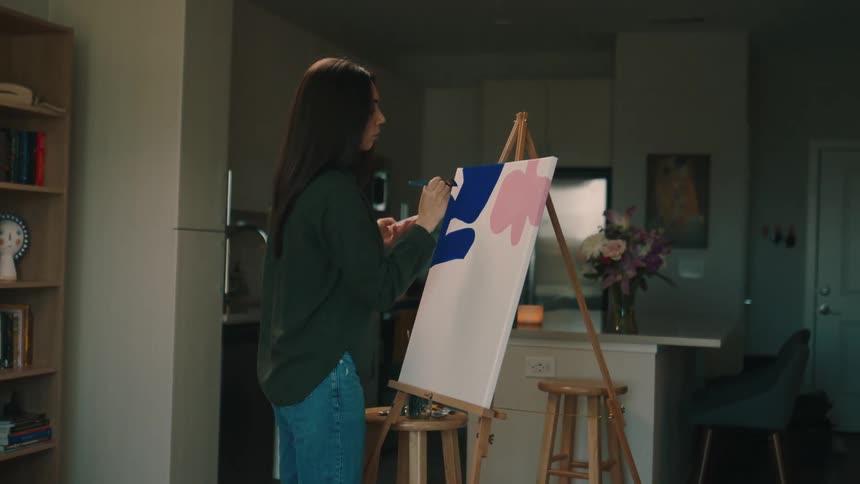 A woman painting colored shapes on a canvas with a brush