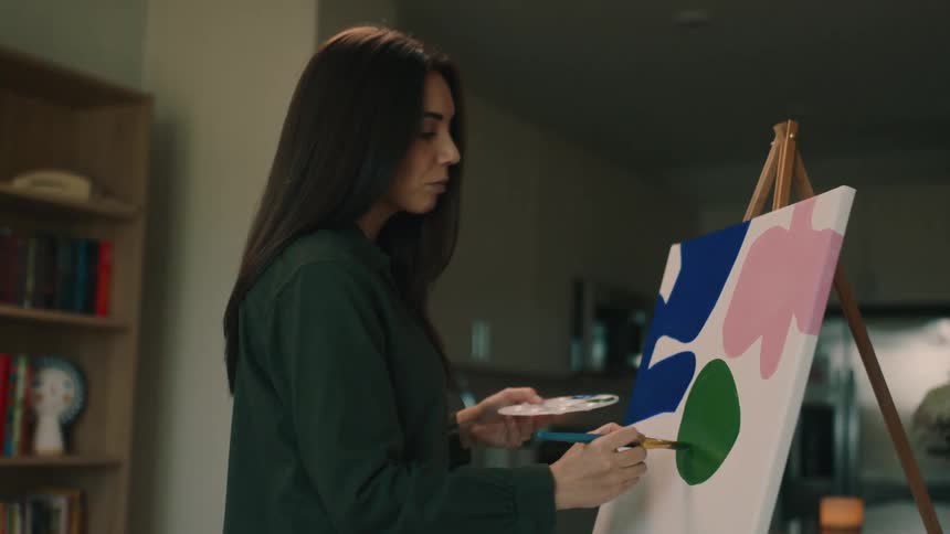 A pretty woman paints shapes on a canvas