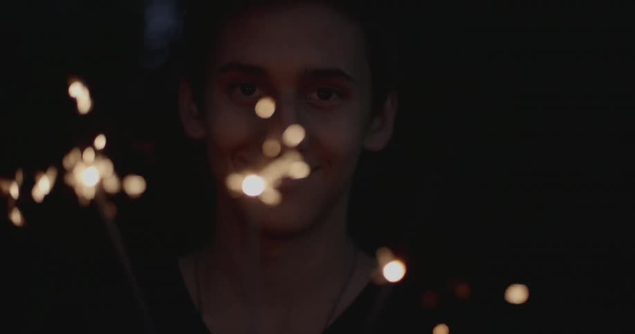 Boy smiles while holding sparklers