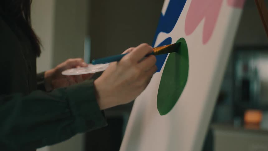 Young woman holding a paint palette and painting a picture