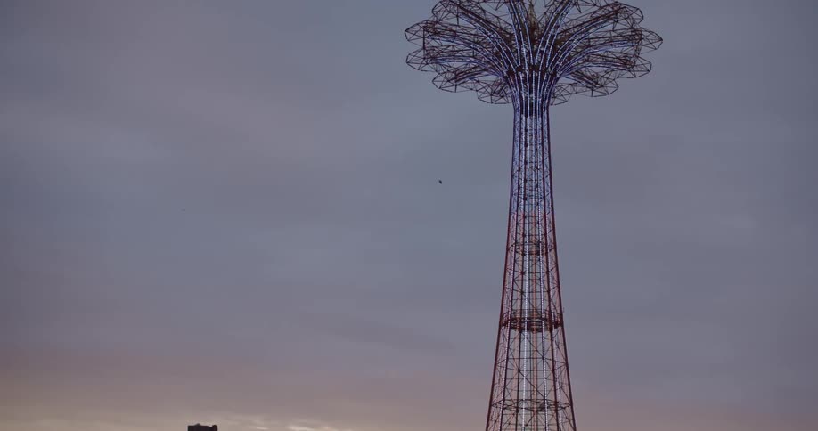 A bird flies in the sky behind a carnival attraction