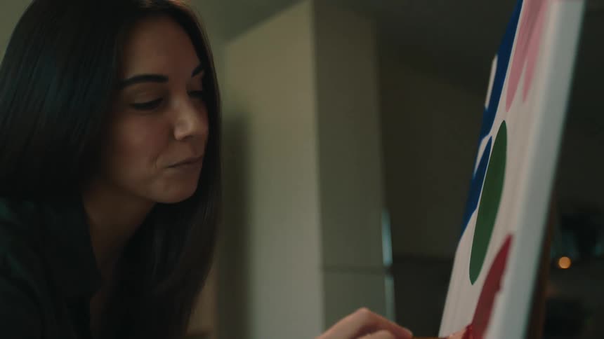 A woman painting colored shapes on a canvas with a brush
