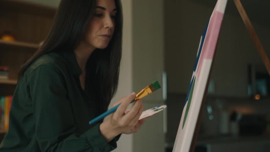 A woman paints art on a canvas in a living room