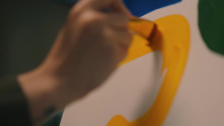 A woman brushes paint onto a canvas