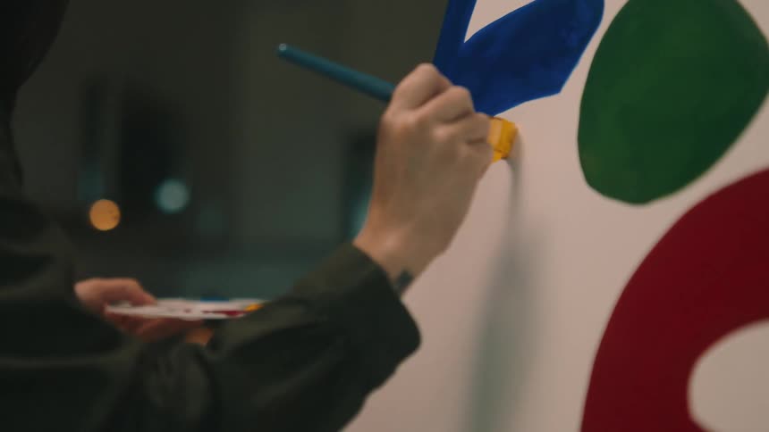 A woman painting colored shapes on a canvas with a brush
