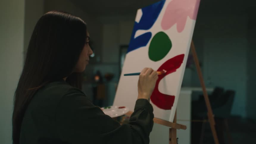 A woman is painting a picture with a brush using the color red