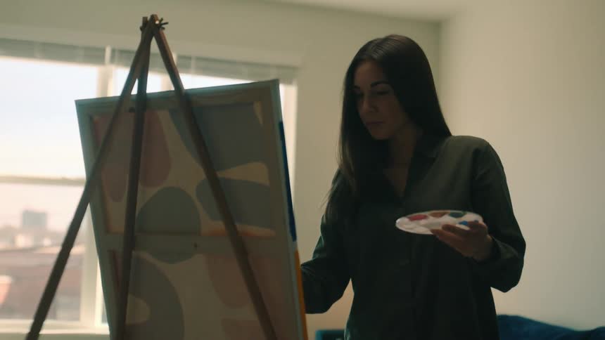 A woman paints an art canvas in an apartment