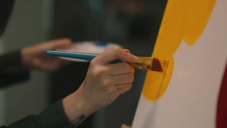 A woman is painting on the canvas