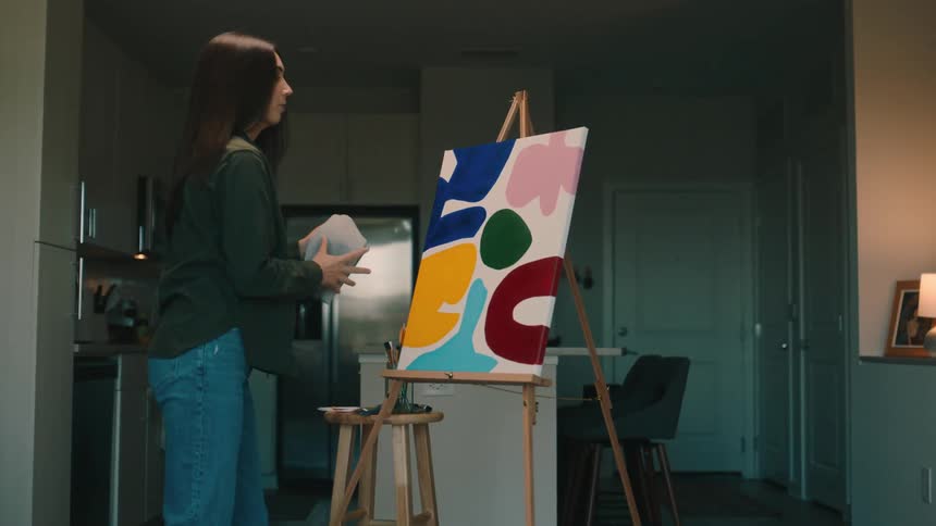 A female artist finishes painting a canvas