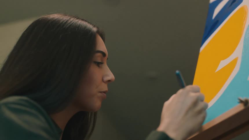 A woman is painting on the canvas