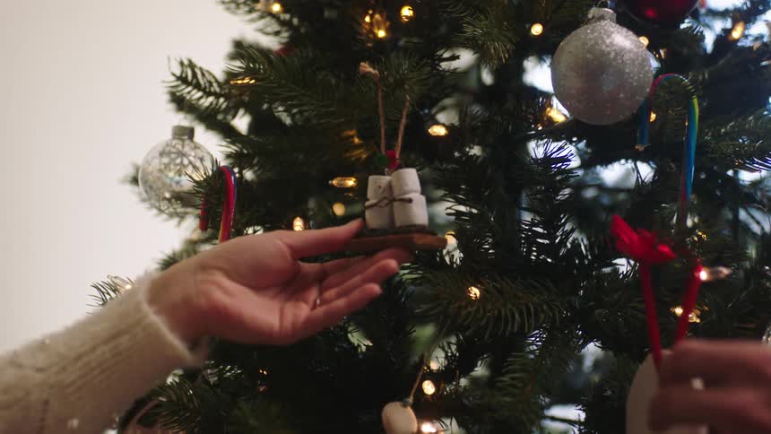 A man and a woman touch ornaments on a tree