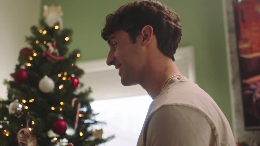 Man and woman smile while decorating christmas tree together