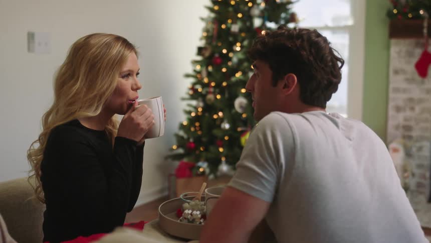 Couple sitting on the sofa talking and having a cup with each other