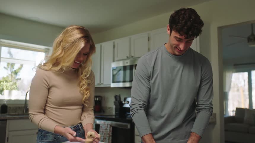 A woman gives a man a kiss as they cook