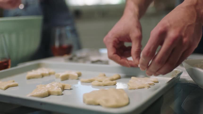 A man next to a woman is happy while placing a cookie in a metal mold