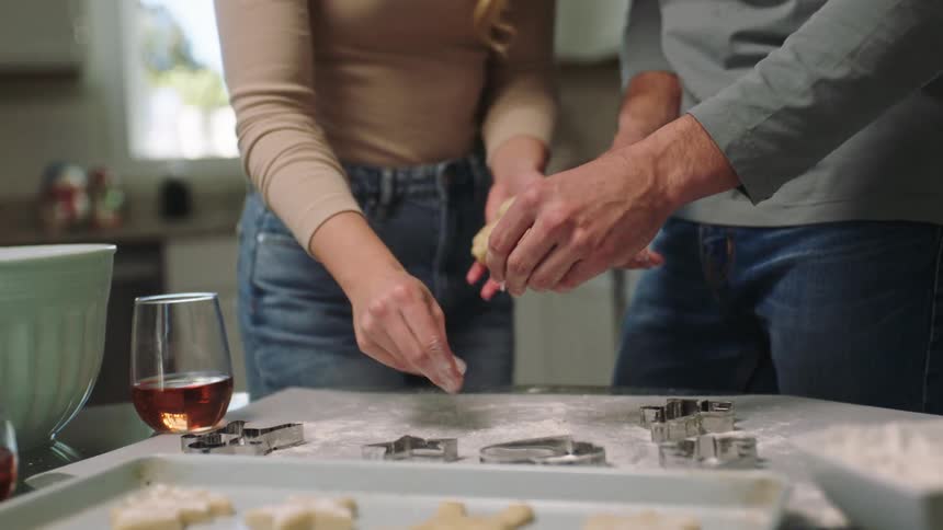 Man and woman at a table preparing dough and cookie shapes