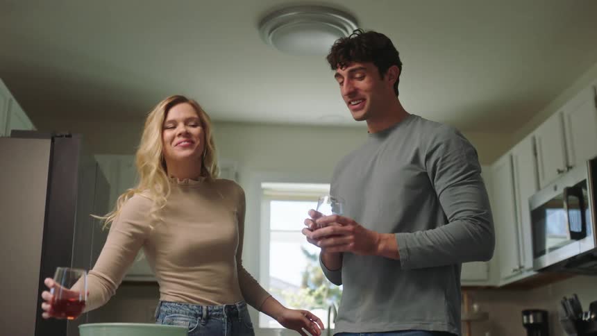 A man and a woman drink alcohol in a kitchen