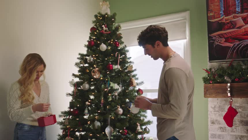 Couple in a room decorating a christmas tree