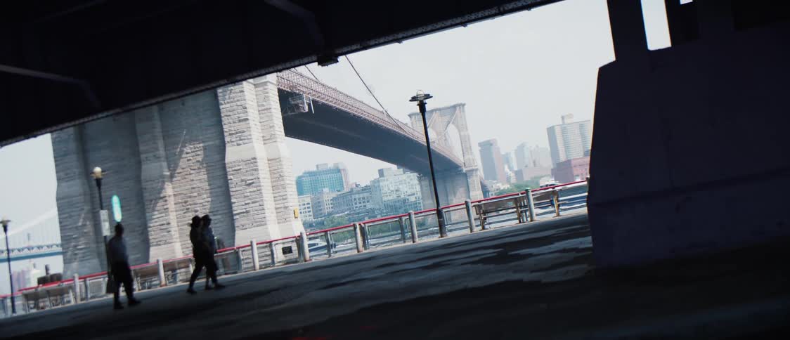 Cars pass as people walk through an underpass next to a bridge