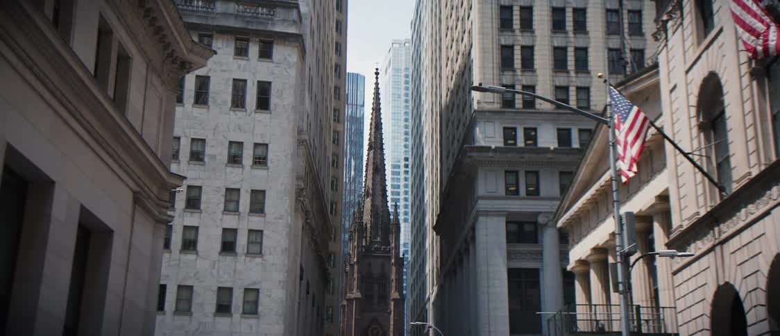 Street in the middle of a city with large buildings and a cathedral in the background
