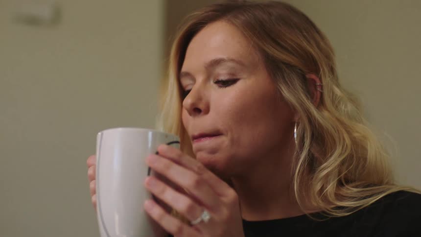 Man and woman sit in living room talking while drinking warm beverages