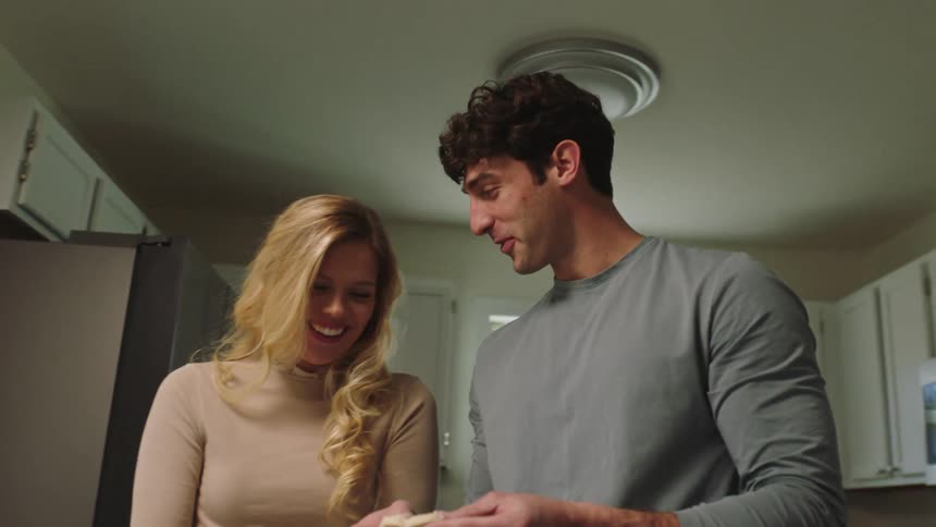 Couple in the kitchen joyfully preparing dough to make cookies