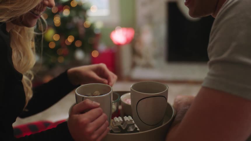 Woman putting sugar in her boyfriends cup while they talk and smile