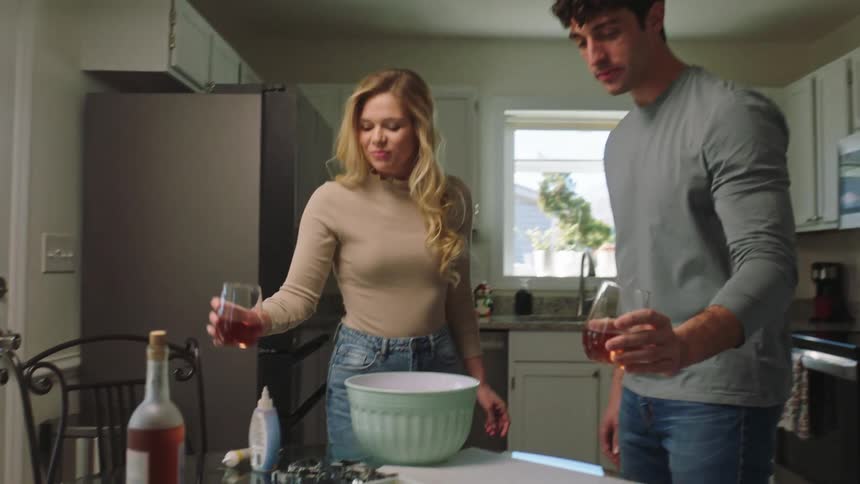 Couple toasting and drinking ros wine standing in the kitchen