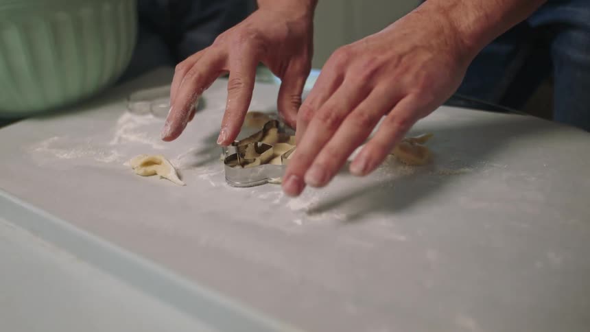 A man uses a cookie cutter on dough