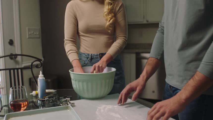Couple in the kitchen using flour and prepared in a smiling way