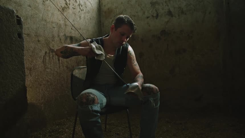 Man cleaning his medieval sword with a cloth while sitting