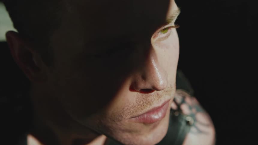 Portrait of a man with green eyes in a dark room with a beam of light under his face