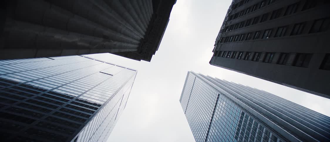 Upward view of mirrored skyscrapers on a cloudy day