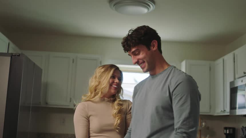 Man and woman embrace in kitchen and make cookies