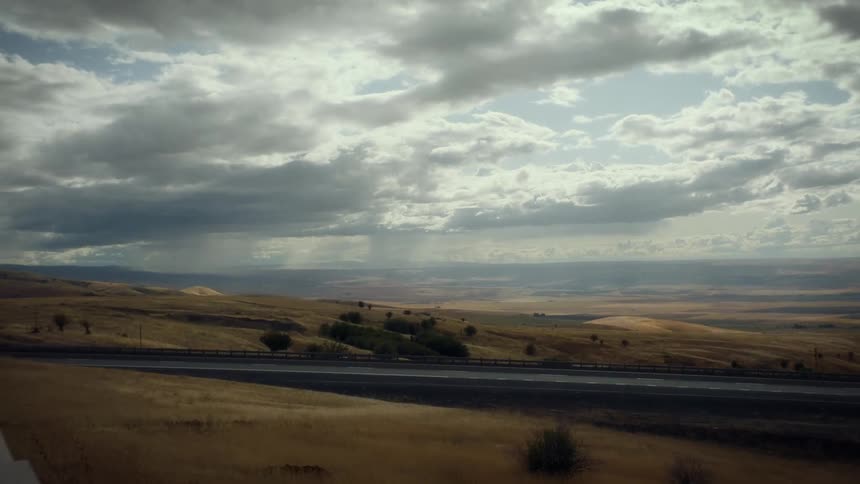 Panorama of a road surrounded by hills on a day with a cloudy sky