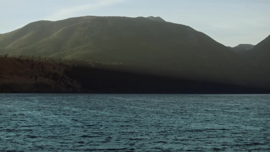 A calm sea surrounded by lush green mountains during the sunny morning