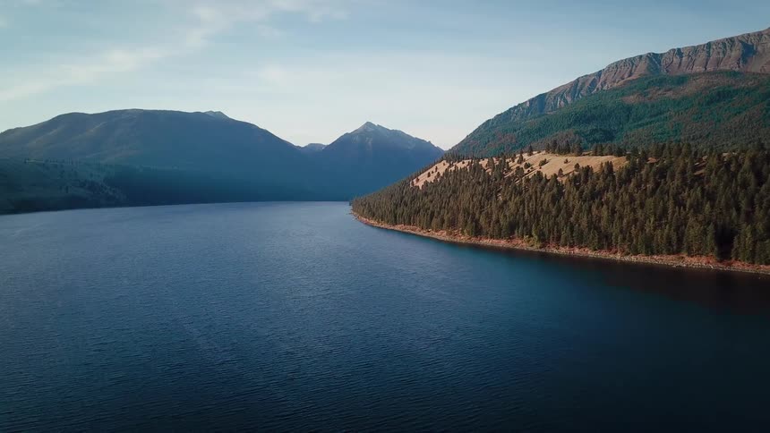Forested shore borders foggy mountains on a cloudy day
