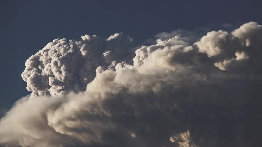 A huge cloud moving against a dark blue sky