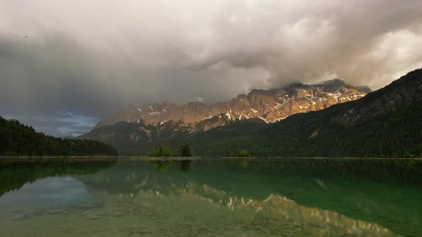 Ducks swim across a lake near a mountain range