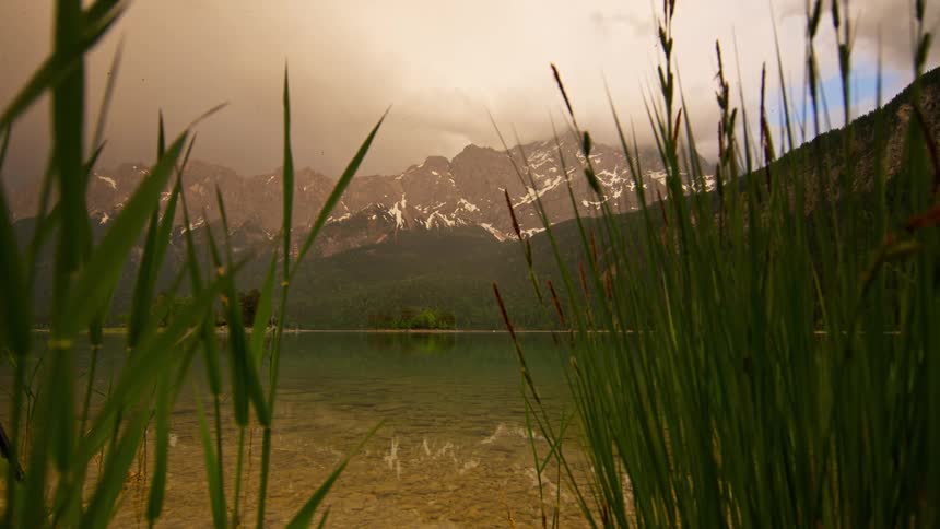 Panorama of a lake with reflections of mountains around it on a cloudy day